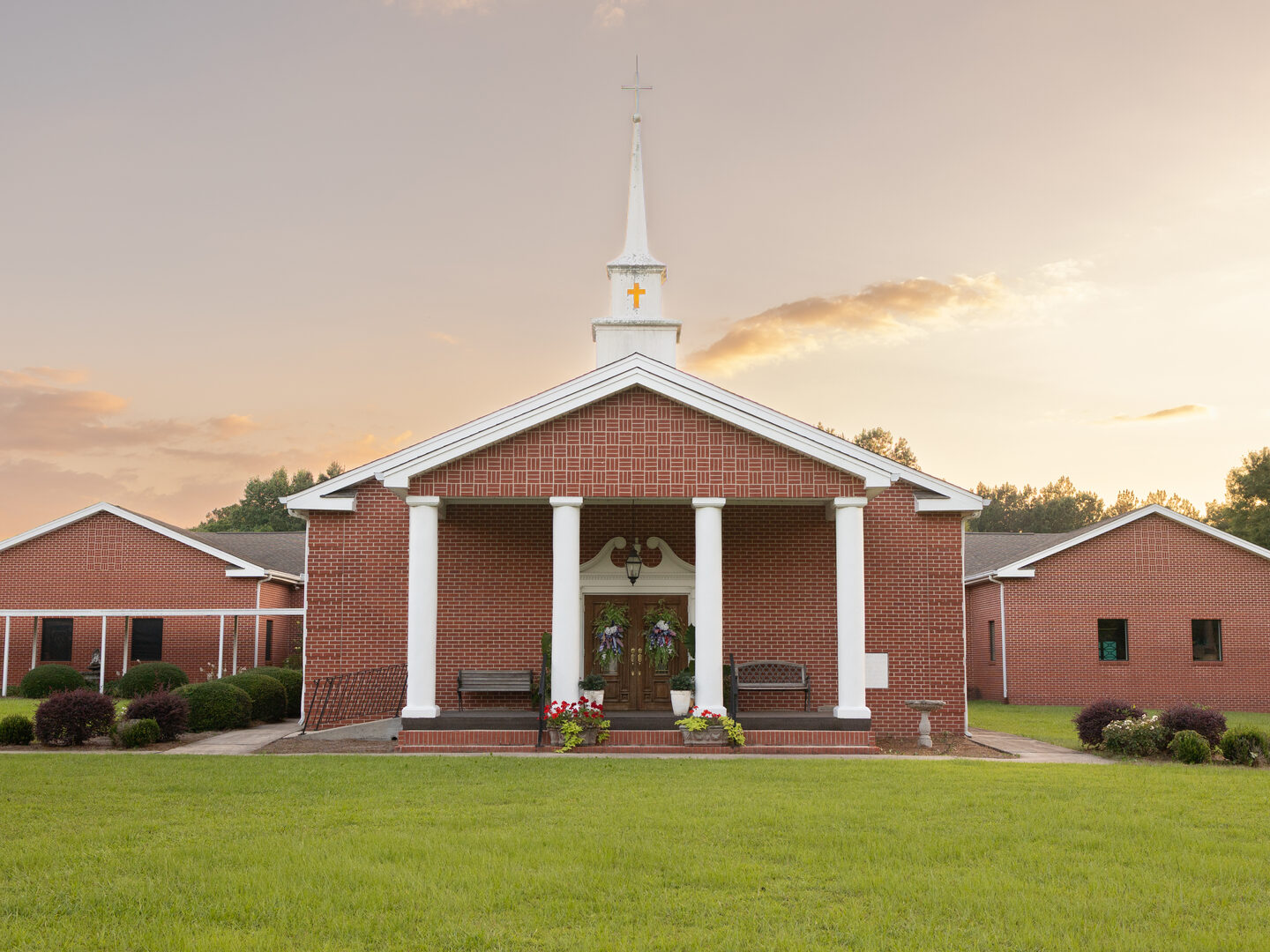 Pleasant Grove Baptist Church building at sunset, with its white steeple and columned front porch